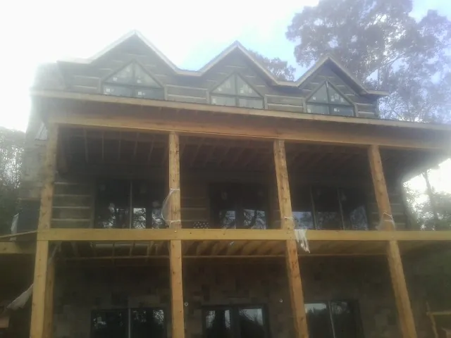 Dormers and porch framing on a large log home under construction — Roof Coating work by our crew in Goodrich