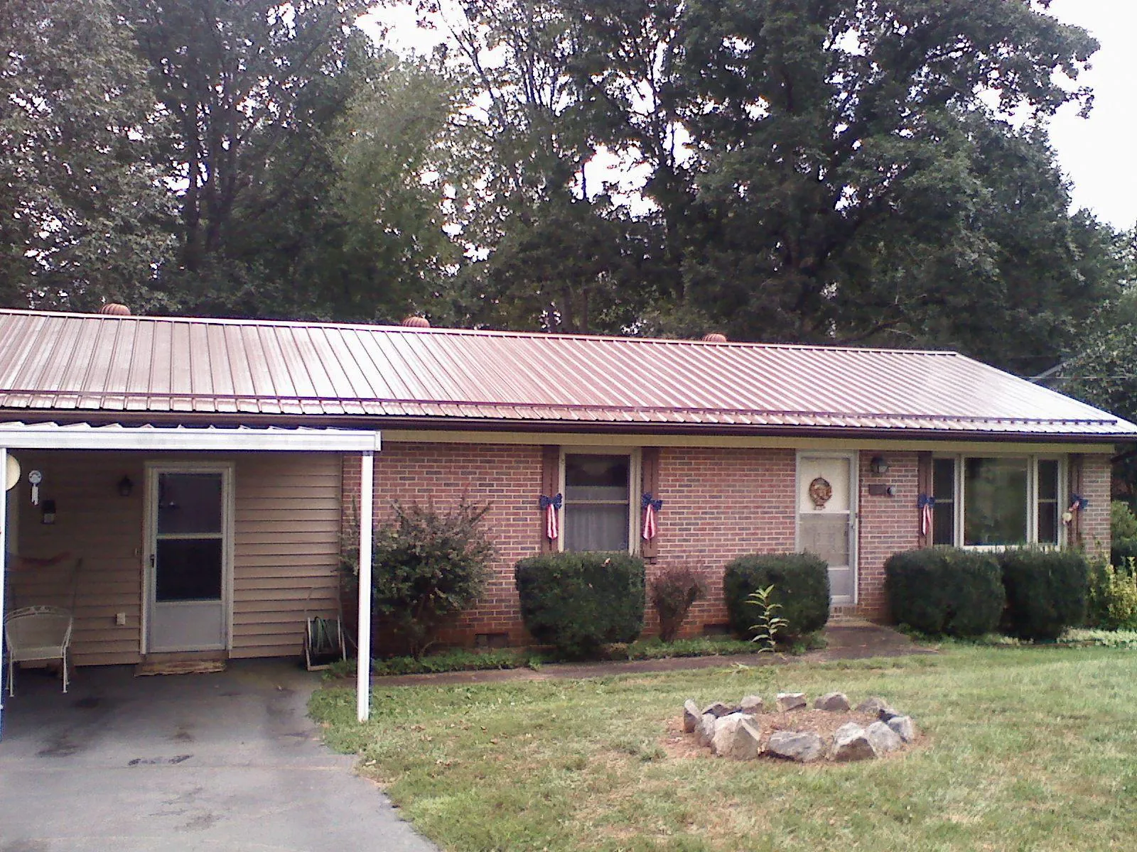 Bronze metal roof and carport on a brick ranch home — Roof Repair work by our crew in Goodrich
