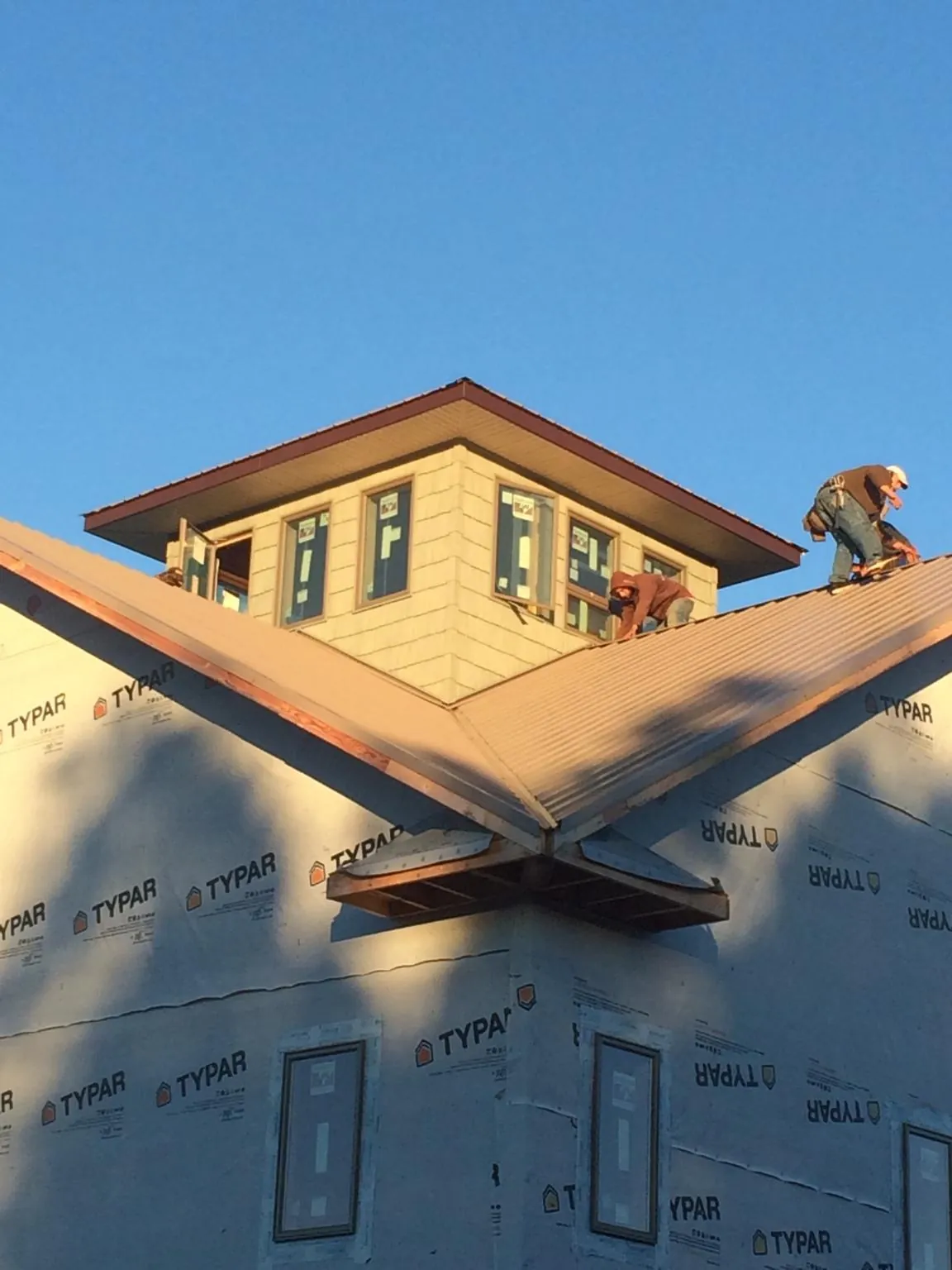 Roofers working around a rooftop cupola on a new metal roof at sunset — Roof Waterproofing in Goodrich by Roofing Brothers